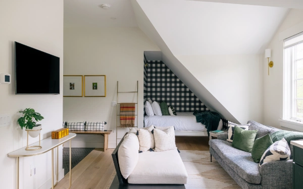 Multi-use living space combining sofa seating, television console, and tucked-in sleeping area with patterned accent wall